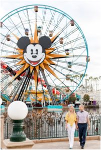Man and woman engagement photography session with couple walking away from the Mickey Mouse Ferris Wheel at Disneyland