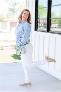 The woman , a Disney World Wedding Photographer, is jumping on one foot having fun with a Disney castle purse and laughing.